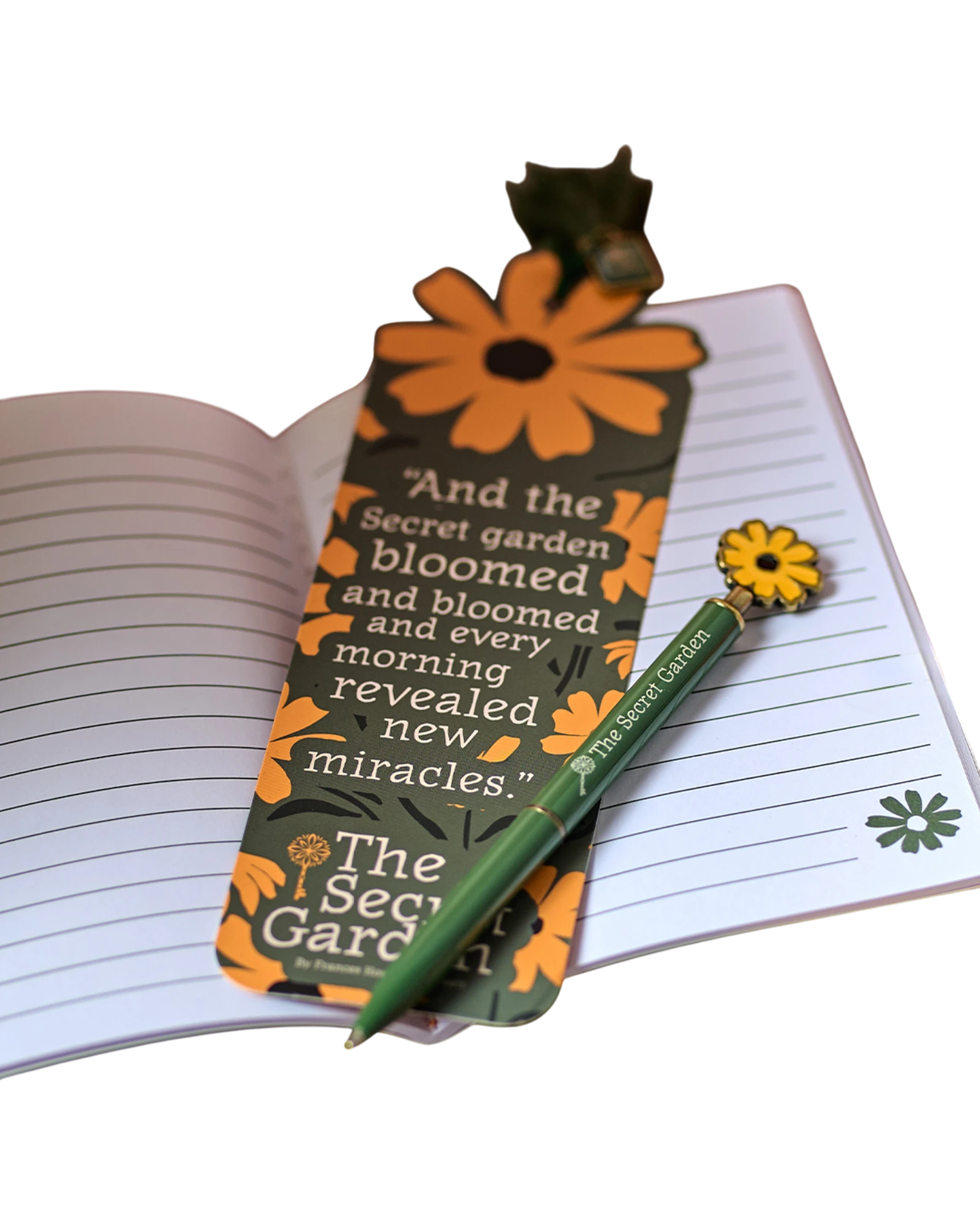 Ripperholics The Secret Garden paper bookmark with orange flower charm and tassel resting on an open lined notebook